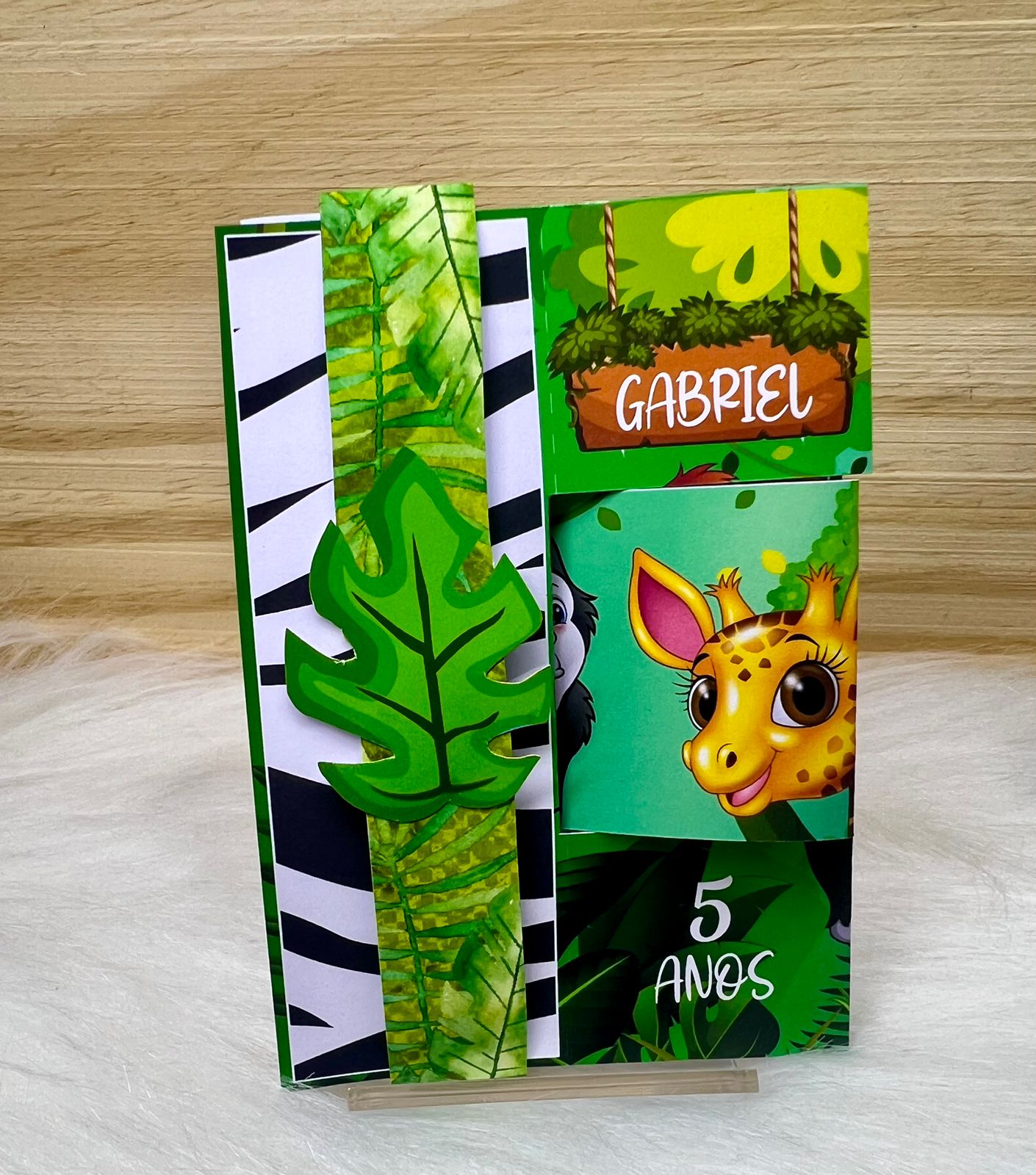 Caixa surpresa montada do Kit Safari, com girafa, folhas verdes e nome Gabriel